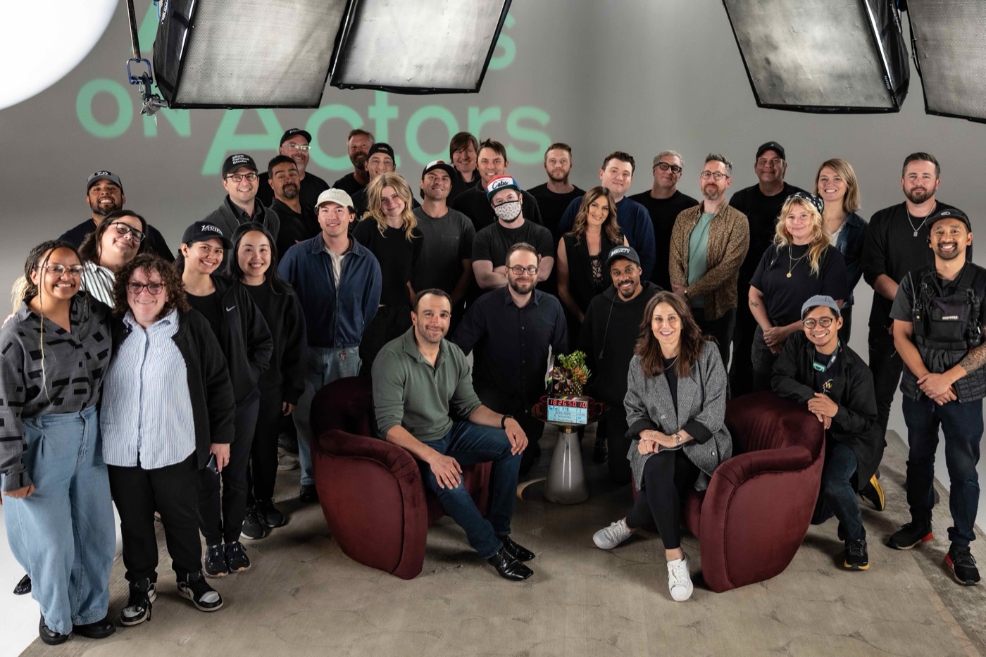 The full cast and crew gathered together on a lit production stage