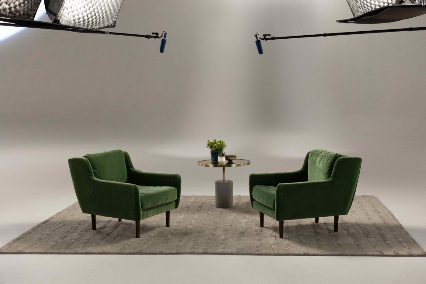 A pair of armchairs lit on a studio set with boom mics overhead