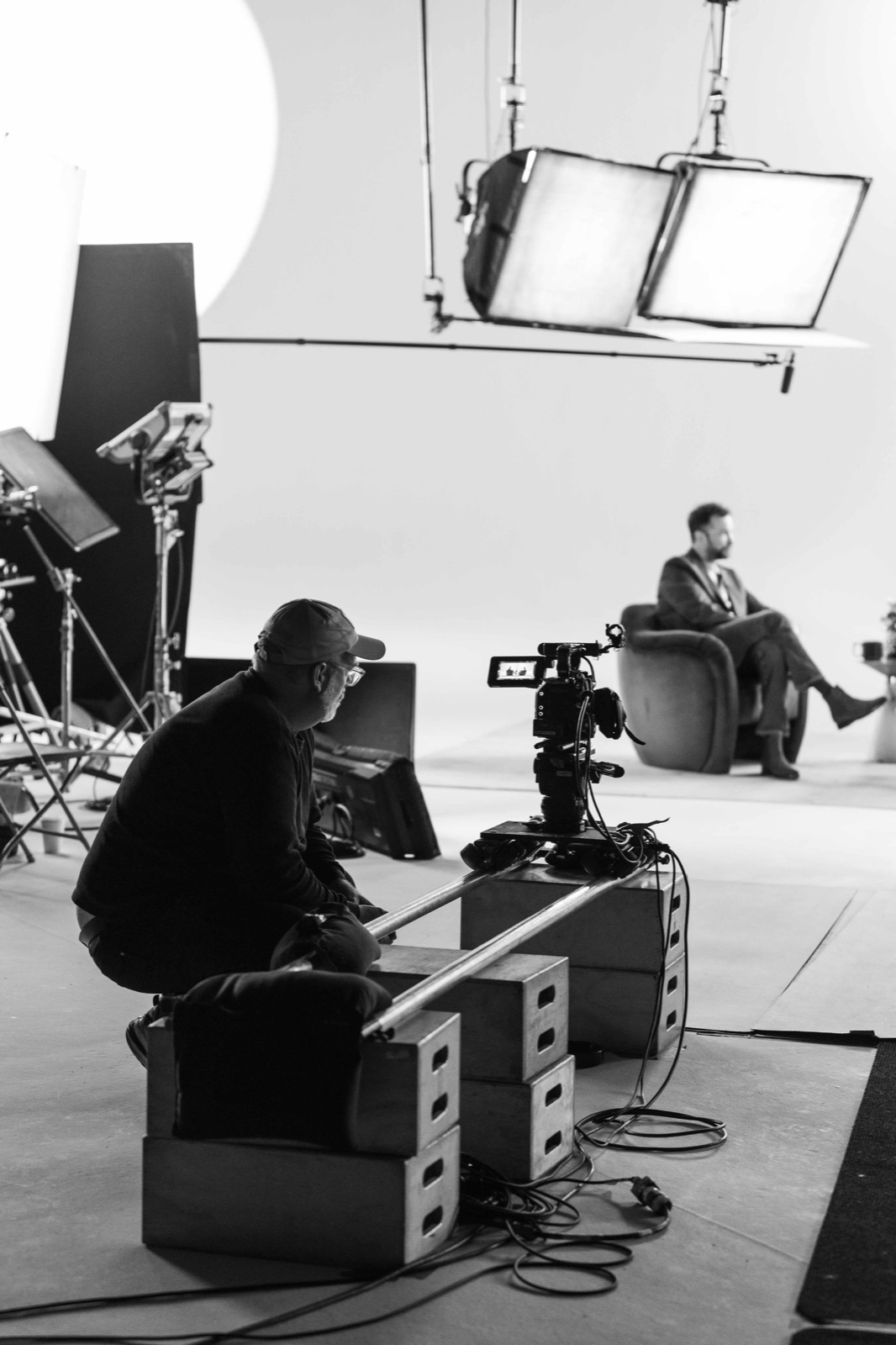 A crew member beside the camera on a lit cyclorama stage during a Lodger Films shoot