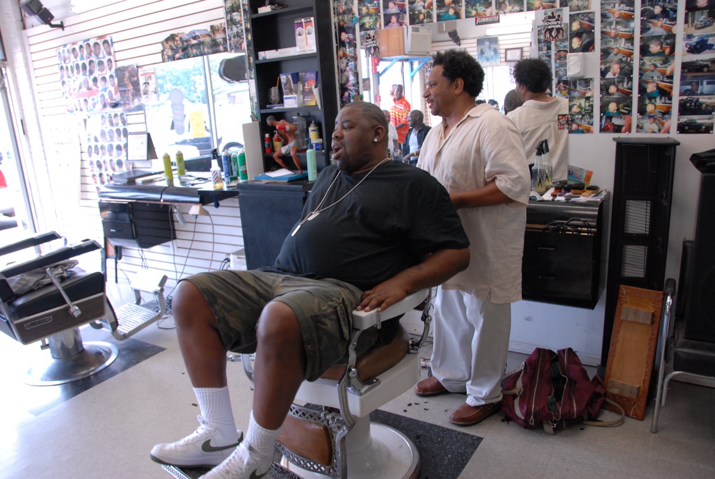 A barber tends to a client reclined in the chair of a neighborhood barbershop location