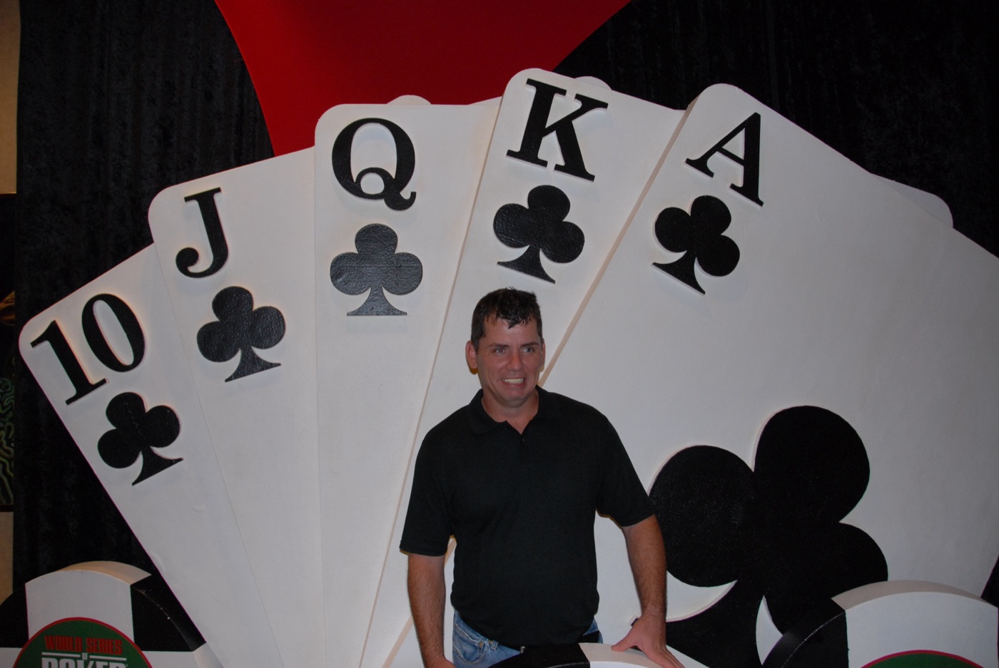A crew member posed in front of giant playing-card set pieces at a World Series of Poker shoot