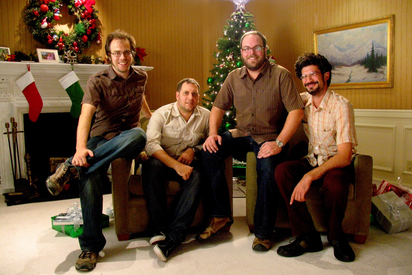 Four Lodger Films crew members posed in armchairs on a Christmas living-room set
