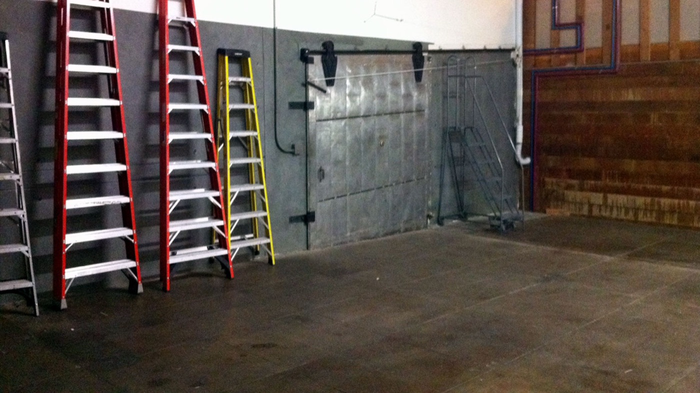 Ladders lined against the wall of the empty Lodger Films stage during build-out